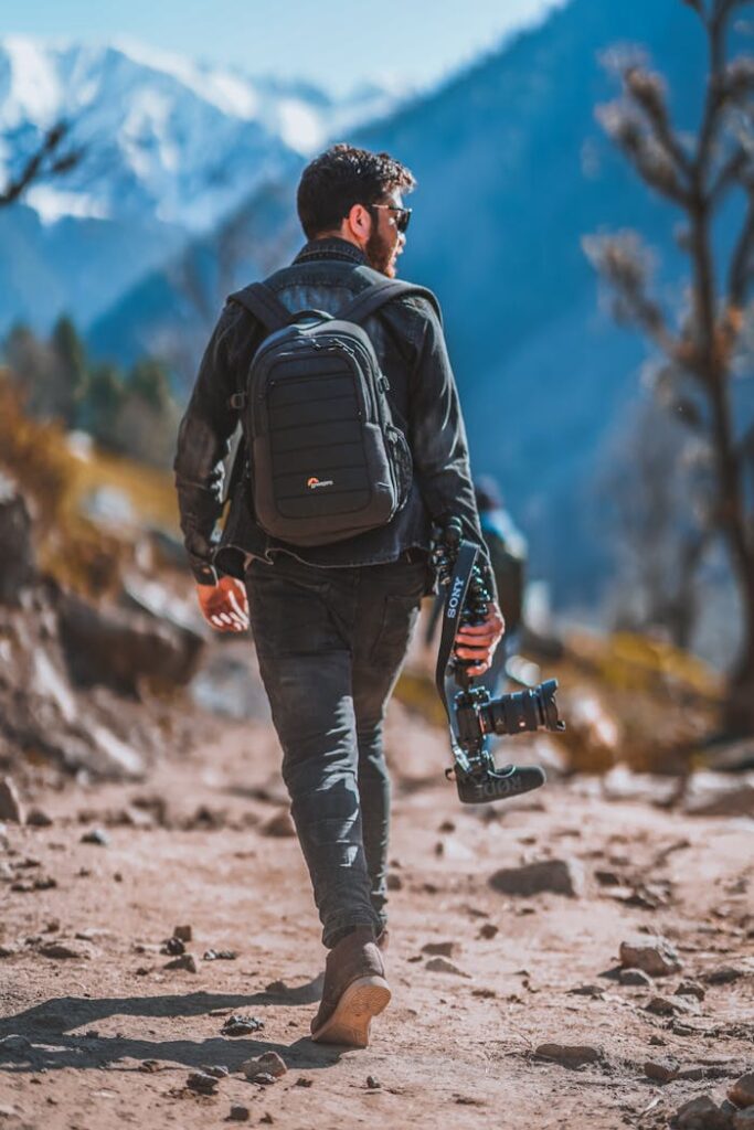 Man hiking in mountains holding a camera, capturing scenic views